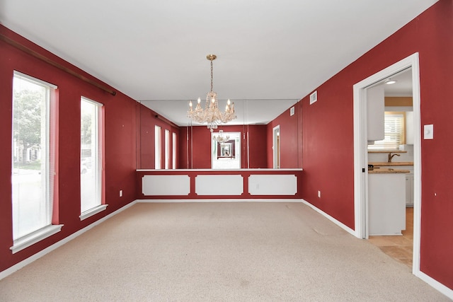 unfurnished dining area with light colored carpet, an inviting chandelier, and sink