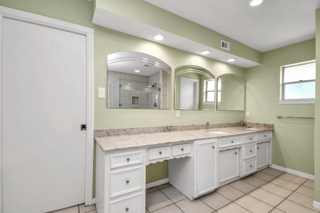 bathroom featuring a tile shower, tile patterned flooring, vanity, and a healthy amount of sunlight