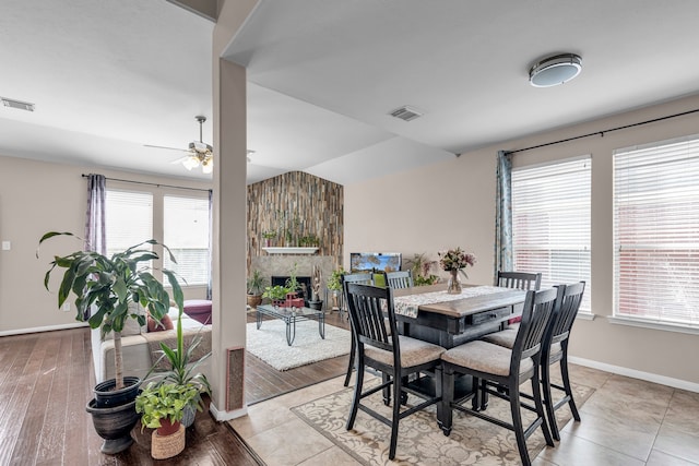 dining room with a fireplace, ceiling fan, light hardwood / wood-style flooring, and a healthy amount of sunlight