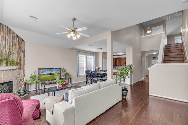 living room featuring a premium fireplace, ceiling fan, and dark wood-type flooring