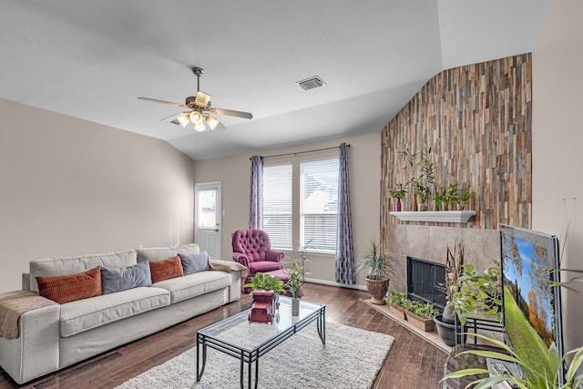 living room with hardwood / wood-style flooring, ceiling fan, a tile fireplace, and vaulted ceiling