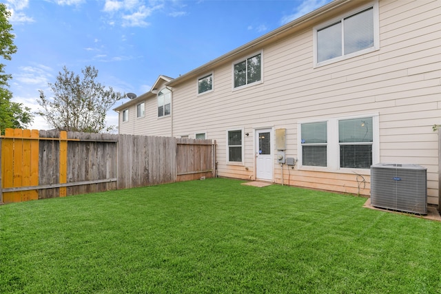 rear view of property featuring cooling unit and a yard