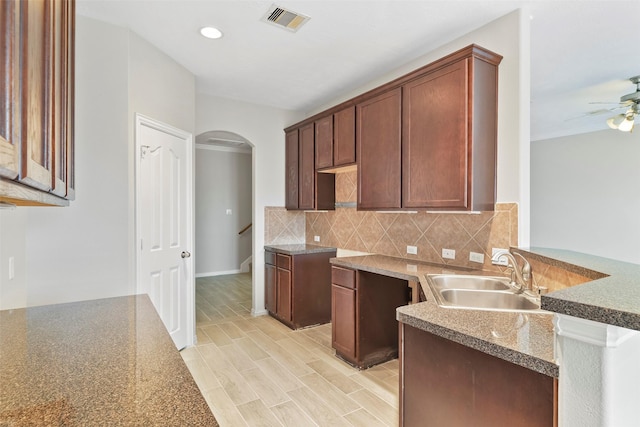 kitchen featuring ceiling fan, sink, tasteful backsplash, light hardwood / wood-style flooring, and kitchen peninsula