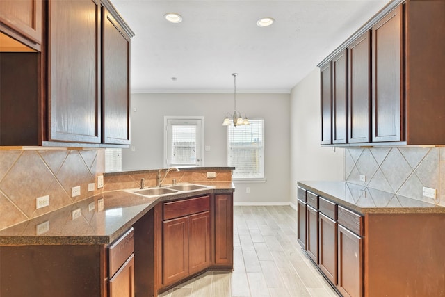 kitchen featuring sink, hanging light fixtures, an inviting chandelier, tasteful backsplash, and light hardwood / wood-style flooring