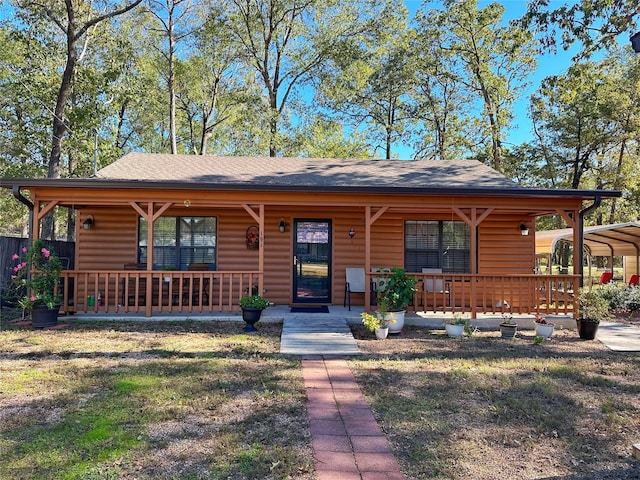 log cabin featuring covered porch and a carport