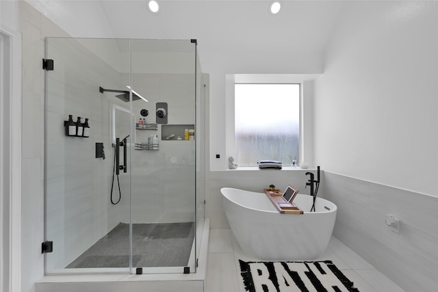 bathroom with separate shower and tub, tile patterned floors, and tile walls