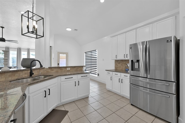 kitchen with stainless steel appliances, sink, white cabinetry, hanging light fixtures, and lofted ceiling