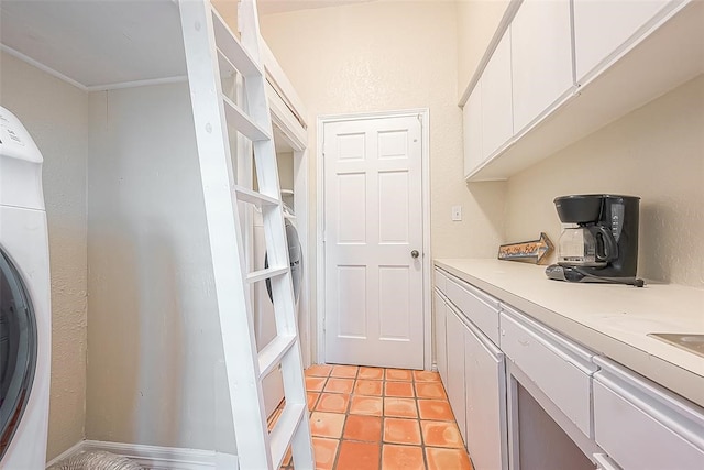 kitchen with white cabinets, light tile patterned flooring, and washer / dryer