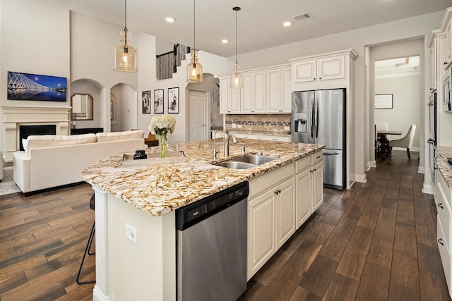 kitchen with stainless steel appliances, dark wood-type flooring, sink, white cabinets, and an island with sink