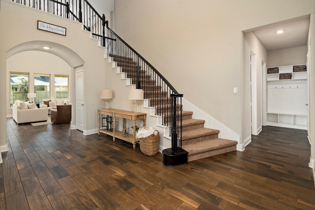 stairway with hardwood / wood-style flooring and a high ceiling