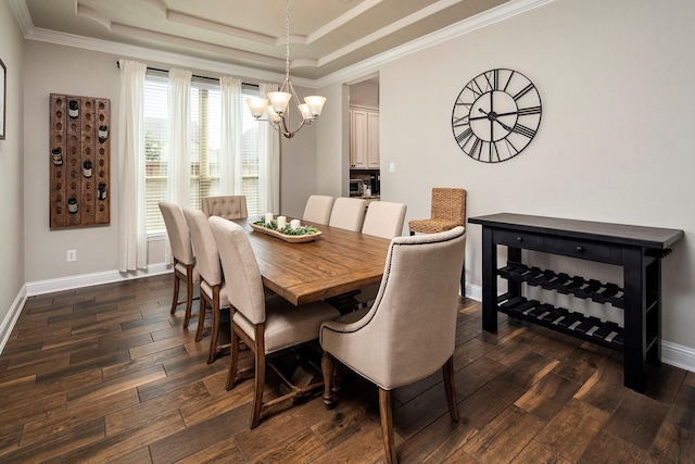 dining area featuring a raised ceiling, a chandelier, dark wood-type flooring, and ornamental molding