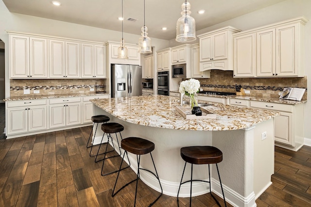 kitchen featuring dark hardwood / wood-style flooring, tasteful backsplash, stainless steel appliances, pendant lighting, and a center island with sink