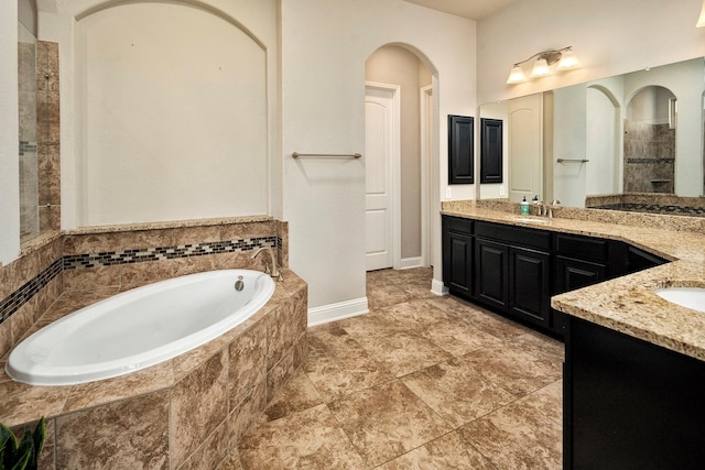 bathroom with vanity and tiled tub