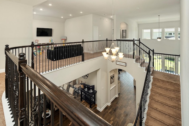 stairway with hardwood / wood-style floors and ceiling fan with notable chandelier