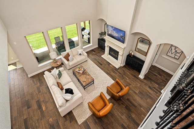 living room with a towering ceiling and dark wood-type flooring