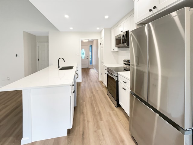 kitchen featuring sink, light hardwood / wood-style flooring, an island with sink, appliances with stainless steel finishes, and white cabinetry