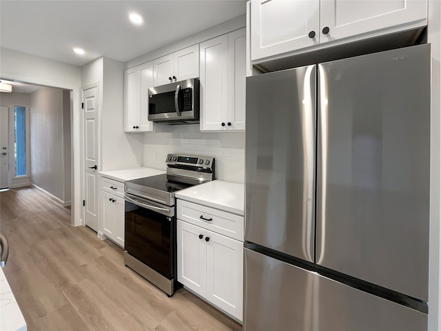 kitchen featuring white cabinets, light hardwood / wood-style floors, backsplash, and appliances with stainless steel finishes