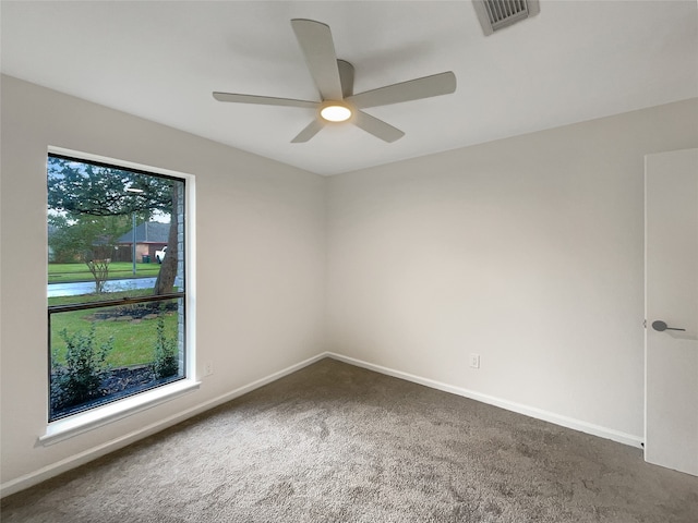 spare room featuring ceiling fan and dark carpet