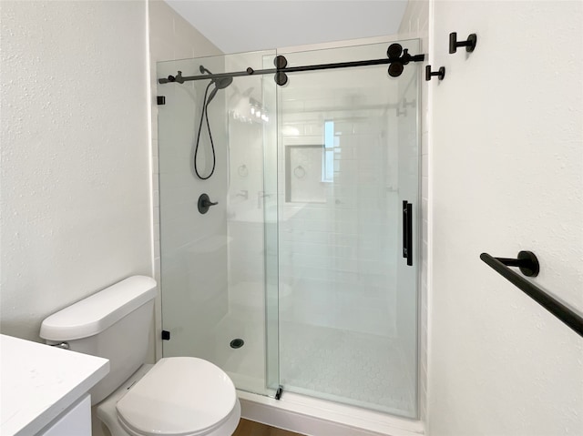 bathroom with a shower with door, vanity, and toilet