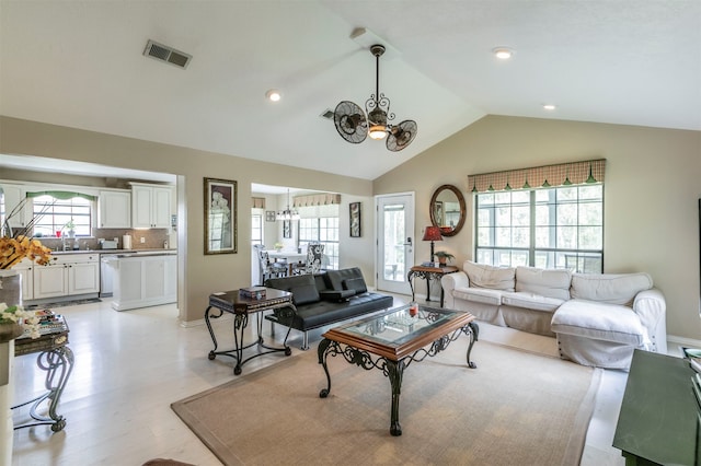 living room with a chandelier, lofted ceiling, and light hardwood / wood-style floors