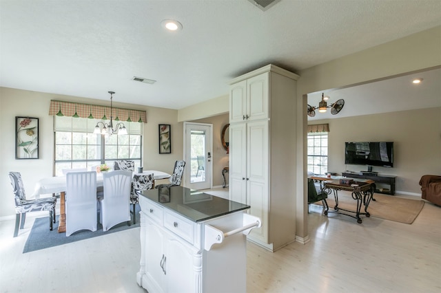 kitchen with white cabinets, light wood-type flooring, and an inviting chandelier