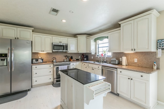 kitchen featuring tasteful backsplash, sink, a kitchen island, and appliances with stainless steel finishes