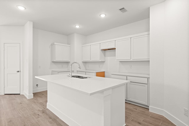 kitchen featuring a kitchen island with sink, light hardwood / wood-style flooring, white cabinets, and sink