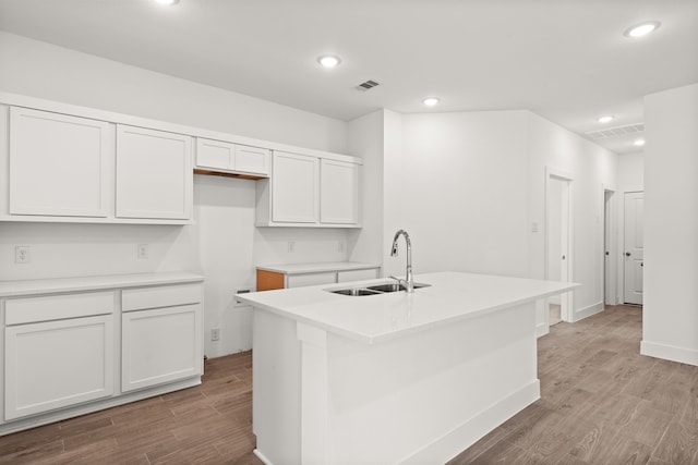 kitchen featuring white cabinets, sink, a kitchen island with sink, and light hardwood / wood-style flooring