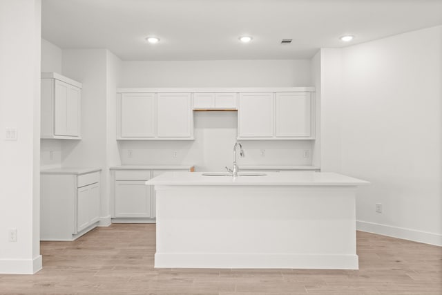 kitchen featuring white cabinetry, sink, and a kitchen island with sink