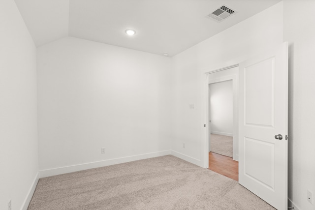 empty room featuring light carpet and vaulted ceiling