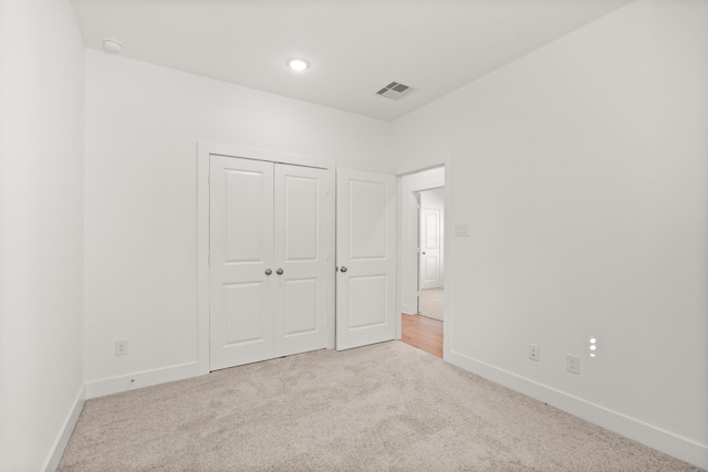 unfurnished bedroom featuring light carpet and a closet