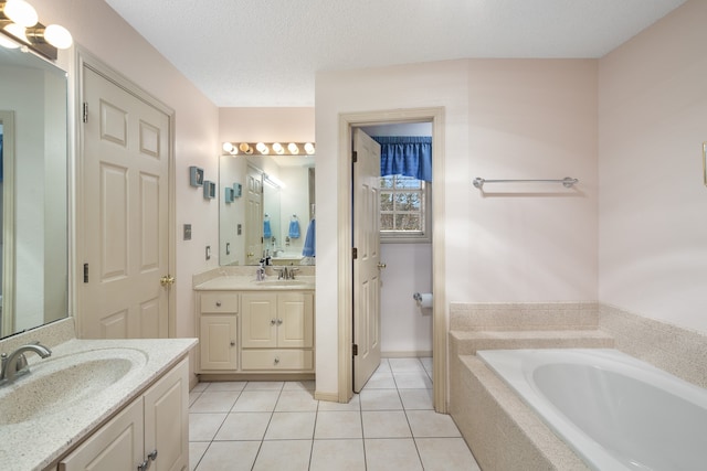 bathroom featuring tiled tub, tile patterned flooring, vanity, and a textured ceiling