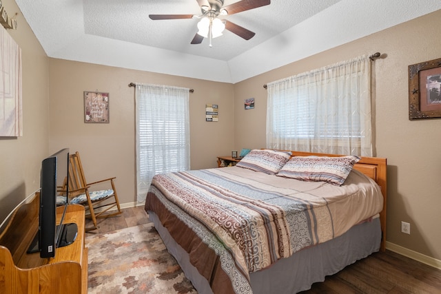 bedroom featuring a textured ceiling, hardwood / wood-style flooring, multiple windows, and ceiling fan