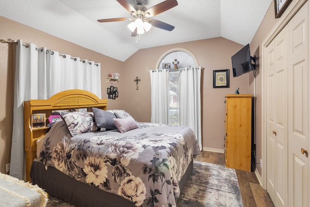 bedroom with a closet, dark wood-type flooring, ceiling fan, and lofted ceiling