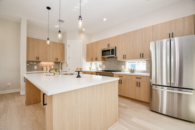 kitchen with sink, light wood-type flooring, an island with sink, and appliances with stainless steel finishes