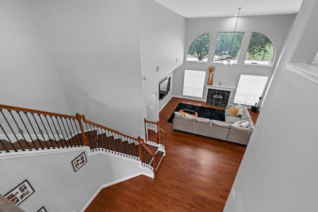 stairs with a tiled fireplace, hardwood / wood-style floors, and high vaulted ceiling