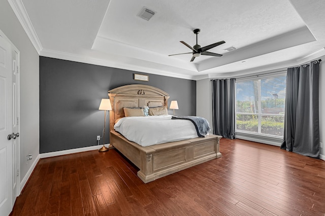 bedroom featuring ornamental molding, a tray ceiling, ceiling fan, and dark wood-type flooring