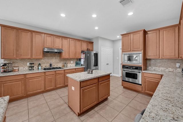 kitchen with a center island, light stone counters, decorative backsplash, light tile patterned floors, and appliances with stainless steel finishes