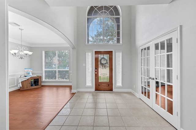 foyer with ornamental molding, light hardwood / wood-style floors, a healthy amount of sunlight, and a notable chandelier