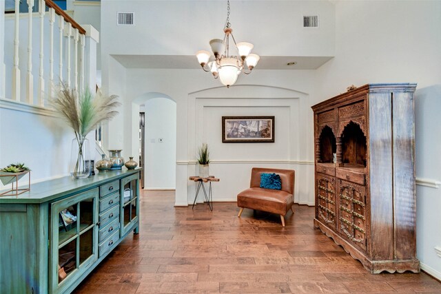 living area with a notable chandelier, wood-type flooring, and a high ceiling