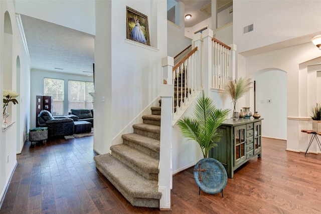 31202 Deerwood Park Ln, Spring City, TX 77386 - stairs with arched walkways, hardwood / wood-style flooring, a towering ceiling, and baseboards