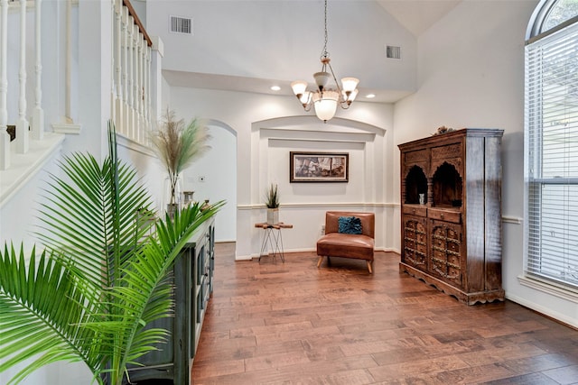 living area with hardwood / wood-style flooring, high vaulted ceiling, and an inviting chandelier