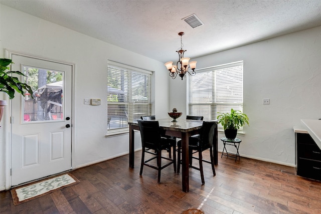 dining room featuring a textured ceiling, dark hardwood / wood-style flooring, and a notable chandelier