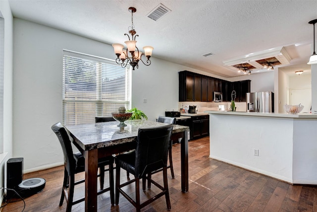 dining room with a textured ceiling, dark hardwood / wood-style flooring, and an inviting chandelier