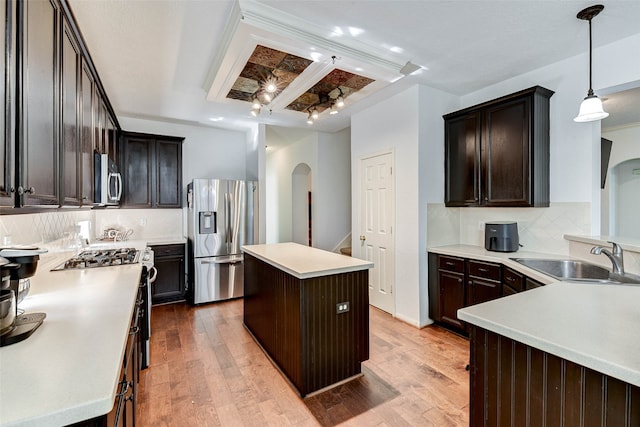 kitchen featuring appliances with stainless steel finishes, pendant lighting, decorative backsplash, a kitchen island, and light wood-type flooring