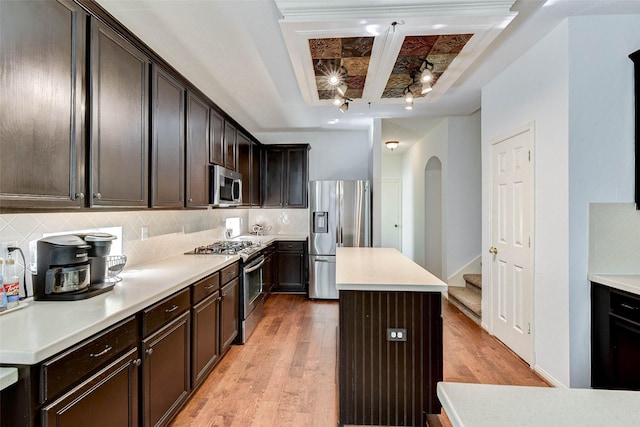 31202 Deerwood Park Ln, Spring City, TX 77386 - kitchen with appliances with stainless steel finishes, a center island, light wood-type flooring, decorative backsplash, and dark brown cabinetry