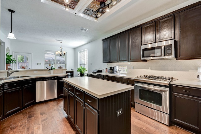 kitchen with hanging light fixtures, sink, a kitchen island, and stainless steel appliances