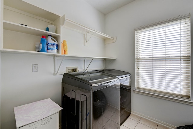 clothes washing area with washer and dryer, a healthy amount of sunlight, and light tile patterned flooring