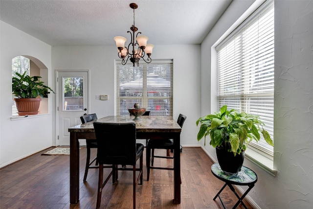 dining room with a chandelier, a textured ceiling, a wealth of natural light, and dark wood-type flooring