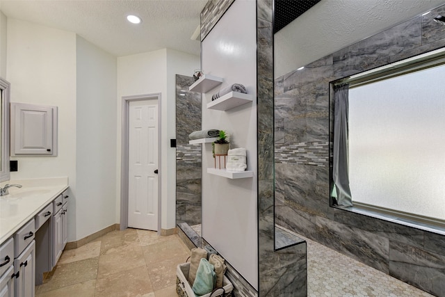 bathroom featuring vanity, a tile shower, a textured ceiling, and tile walls